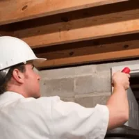 Termite inspection technician checking a basement wall and framing for termite activity in Memphis, TN